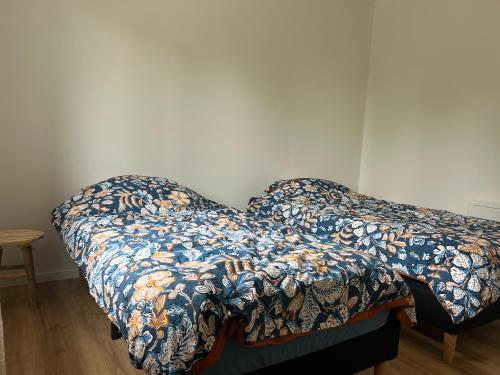 a bed with a comforter on it in a room at Le Bonheur Normand à la Mini Ferme in Bournainville