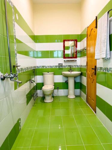 a green and white bathroom with a toilet and sink at Infinity Hotel in Lahore
