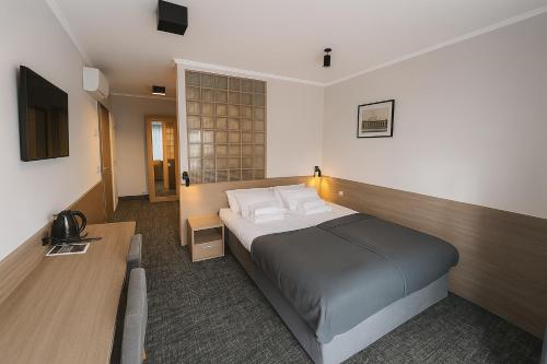 a hotel room with a bed and a desk at Willa Zdrojowa PARK Sauna, Jacuzzi, Fitness in Busko-Zdrój
