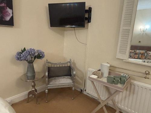 a living room with a vase of flowers and a tv at Simonburn Bed and Breakfast 