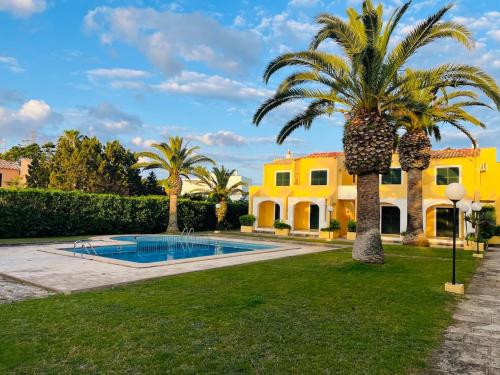 Reserva septiembre,octubre Apartamento piscina y playa junto Cap D Artrutx cerca Ciudadela في سون كسورغير: بيت اصفر مع نخله ومسبح