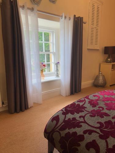 a bedroom with a bed and a window with curtains at Simonburn Bed and Breakfast 