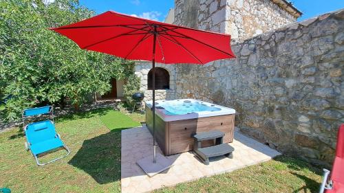 a hot tub with a red umbrella and a chair at Villa Bartola in Grižane