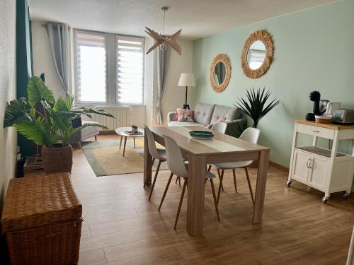 a dining room with a table and chairs and a living room at Confort & style dans ce joli appartement de 44 m2, chambre séparée, PLEIN CENTRE de Dole in Dole
