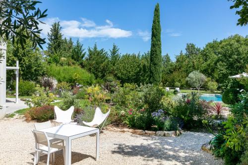a patio with a table and chairs and a garden at La Bastide de Damien, 5 clefs Demeure d'Exception et Table Remarquable dans le guide Teritoria, JACUZZI Privatif, Cuisine étoilée Dominique Frérard in Aix-en-Provence