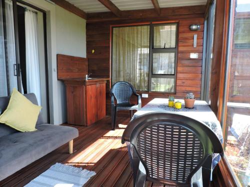 a screened in porch with a table and chairs at Droom Verlore in Jeffreys Bay