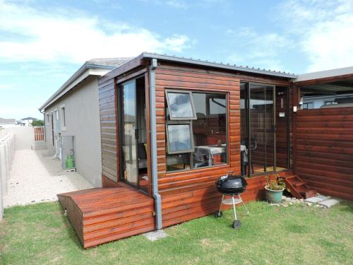 a wooden house with a grill in the yard at Droom Verlore in Jeffreys Bay
