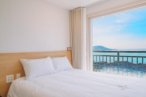a bedroom with a bed and a view of the ocean at Jeju Mon Dieu Hotel in Jeju