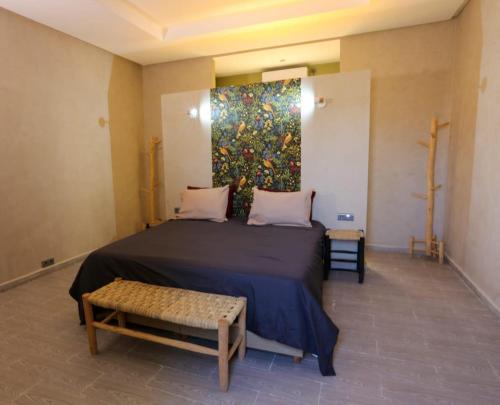 ein Schlafzimmer mit einem Bett und einem Gemälde an der Wand in der Unterkunft Belgium Camp & Rooms jbilat Marrakesh 