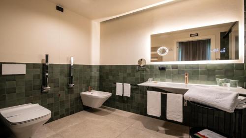 a bathroom with a sink and a toilet and a mirror at Terme Preistoriche Resort & Spa in Montegrotto Terme