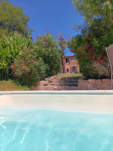 - une piscine en face d'une maison fleurie dans l'établissement Chambres 2 personnes dans notre maison Girondine, à Saint-Martin-de-Lerm