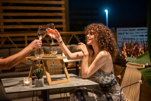a man and woman sitting at a table drinking wine at Ostria Sea Side Hotel in Hanioti