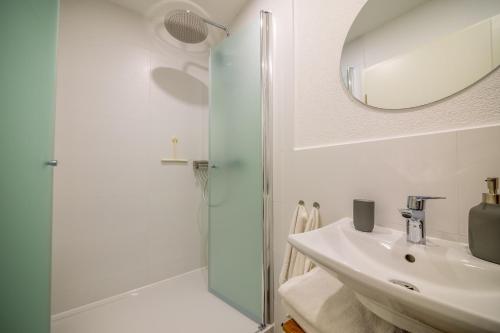 a white bathroom with a sink and a shower at Sixtn Apartments Bühlertal in Bühlertal