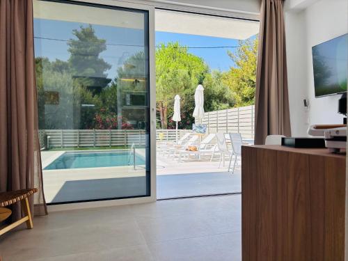 a living room with a sliding glass door leading to a swimming pool at Zorbas Family Villas in Skiathos Town