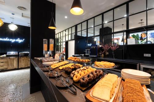 a buffet line with different types of bread and pastries at Dormirdcine Alicante in Alicante