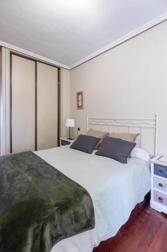 a bedroom with a large white bed with blue pillows at San Anton, Ventana al mar in Llanes