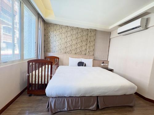 a bedroom with a large bed and a crib at Tc慢旅花蓮館-近東大門夜市市中心 in Hualien City