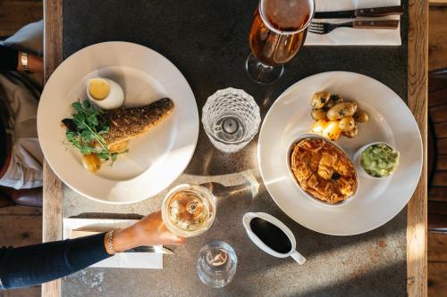 a table with two plates of food and a person holding a glass at The Royal Hotel in Bideford