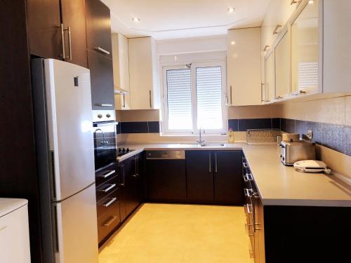 een keuken met zwarte kasten en een witte koelkast bij Simple Joys Apartment in Bar