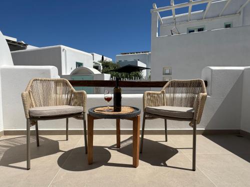 two chairs and a table with a bottle of wine at Theofanis Studios in Agia Anna Naxos