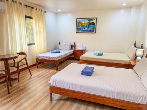a room with three beds and a table and a table at Tessie's Home Stay Bed & Breakfast in Puerto Princesa City