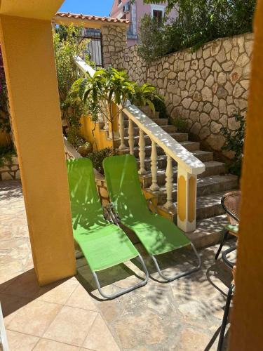 two green chairs on a patio with a staircase at La Meri in Čunski