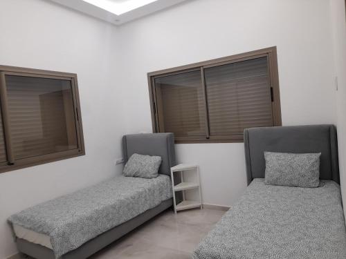 two beds in a room with two windows at Villa Mimouche in Taroudant