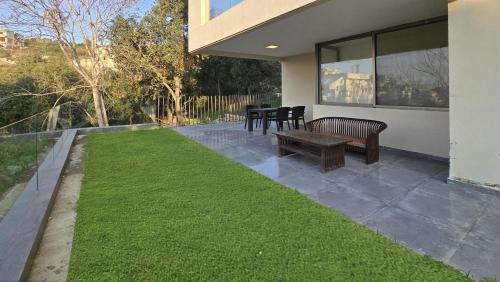 a patio with a bench and a grass yard at Tabarja Hills apartment in ‘Ayn aş Şughayrah