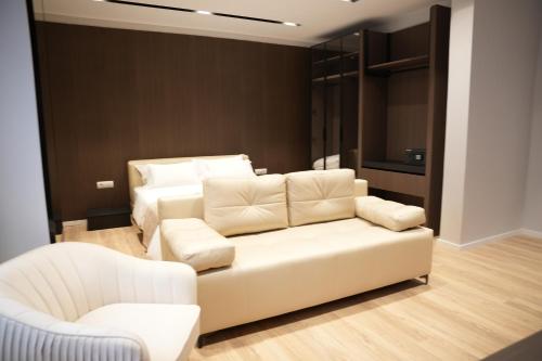 a living room with a white couch and two chairs at Hotel Aquila D in Durrës