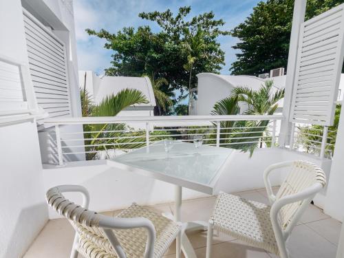 a white balcony with a glass table and chairs at Le Beachclub in Pereybere