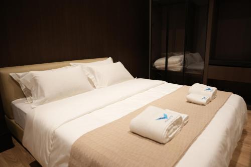 a large white bed with two folded towels on it at Hotel Aquila D in Durrës