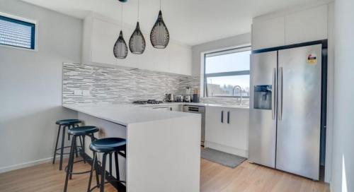 a kitchen with a refrigerator and some bar stools at Tranquil 4 Bed Family Retreat 5Min To Airport in Christchurch