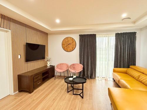a living room with a couch and a table and a clock at Tranquil 4 Bed Family Retreat 5Min To Airport in Christchurch