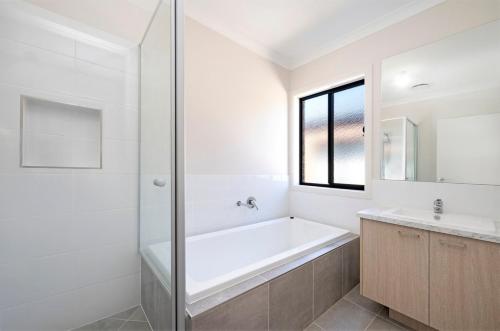 a white bathroom with a tub and a sink at MV-Giraffe 4 bedroom x 3 bathroom in Hamilton