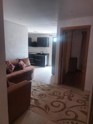a living room with a couch and a kitchen at Très joli appartement vue sur parc 5 min de la plage du centre mohammedia in Mohammedia