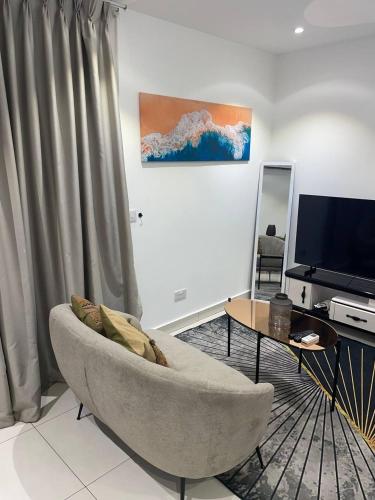 a living room with a couch and a television at Lennox Serviced Apartments in Accra