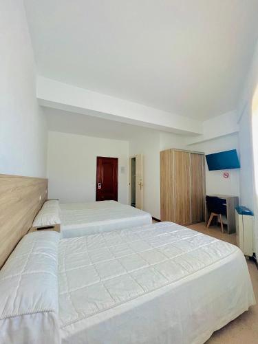 a large bedroom with two beds and a desk at Pensión Costiña in Noya