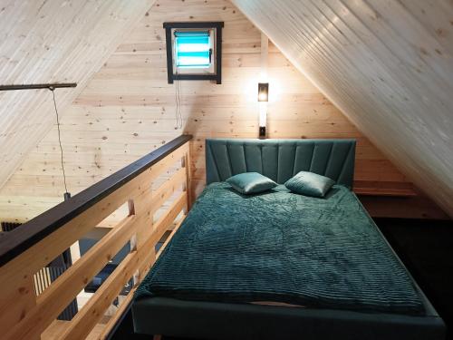 a bedroom with a green bed in a attic at Domki Kompas in Jantar
