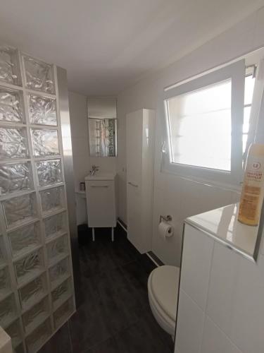 une salle de bain blanche avec toilettes et fenêtre dans l'établissement AS14629 - P2 Mezzanine avec vue mer latérale, dans une résidence sur plage avec parking privé, au Grau-du-Roi