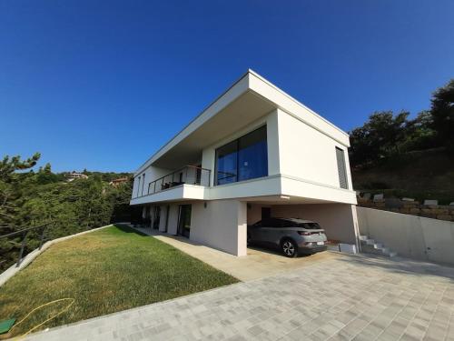 a white house with a car parked in the driveway at Apartment La Lita in Šmarje