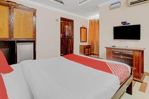 a bedroom with a bed and a flat screen tv at Hotel O Royal Grand Residency Near Lalbagh Botanical Garden in Bengaluru