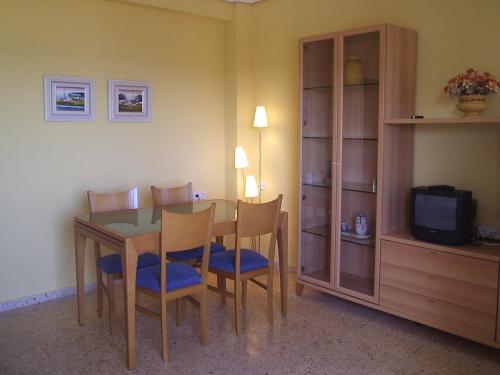 ein Esszimmer mit Tisch und Stühlen und einem Fernseher in der Unterkunft Apartamento con vistas al mar in Piles