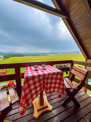 a table with a red and white checkered table cloth on a deck at Mountain Viewpoint in Žabljak