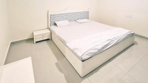 a white bedroom with a bed and a night stand at Tabarja Hills apartment in ‘Ayn aş Şughayrah
