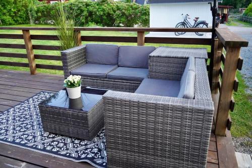 a patio with wicker furniture on a wooden deck at Entire house with hot tub and beachfront in Köping