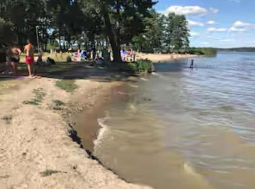 a group of people on a beach near the water at Entire house with hot tub and beachfront in Köping