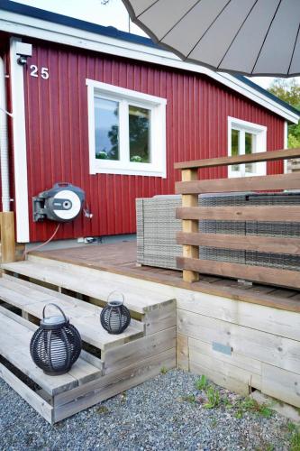 a deck with two black pots in front of a red building at Entire house with hot tub and beachfront in Köping