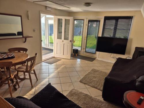 Una sala de estar con un sofá, una mesa y un televisor. en 8 The Coombe, en Kilkhampton