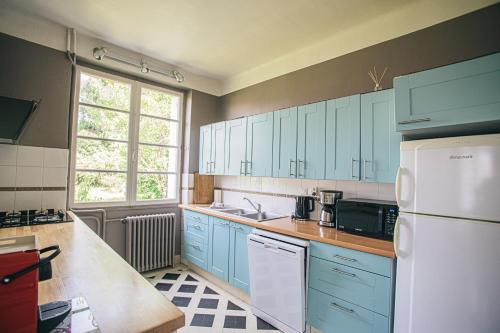 La cuisine est équipée de placards bleus et d'un réfrigérateur blanc. dans l'établissement 