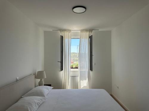 プーラにあるFiorea Apartmentのベッドと窓のある白い寝室